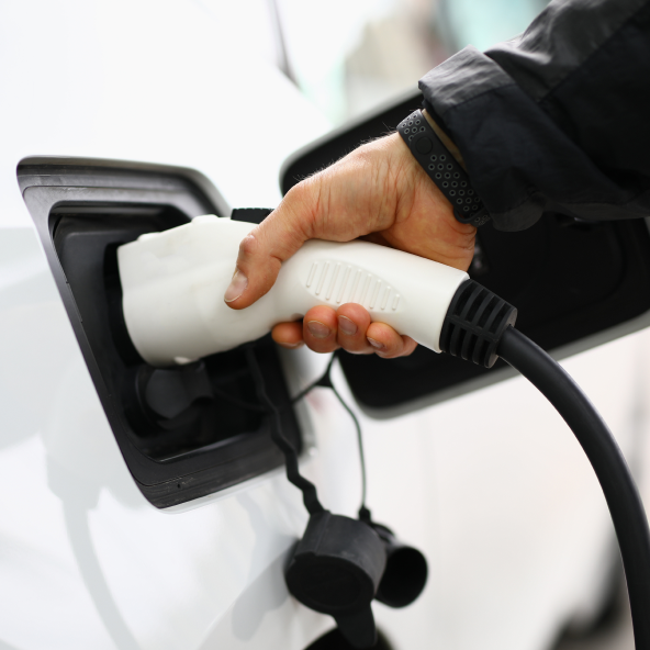 mężczyzna podpina do prądu auto elektryczne