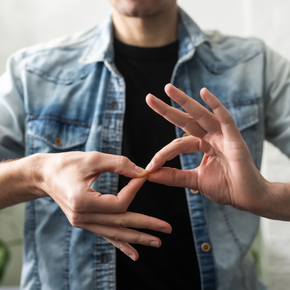Mężczyzna układający dłonie w znak języka migowego.