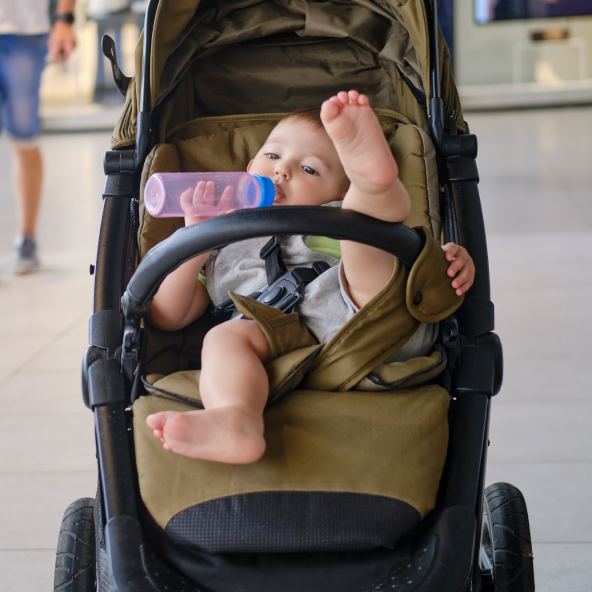 Małe dziecko w wózku lezy z wyciągniętą jedną nogą do góry