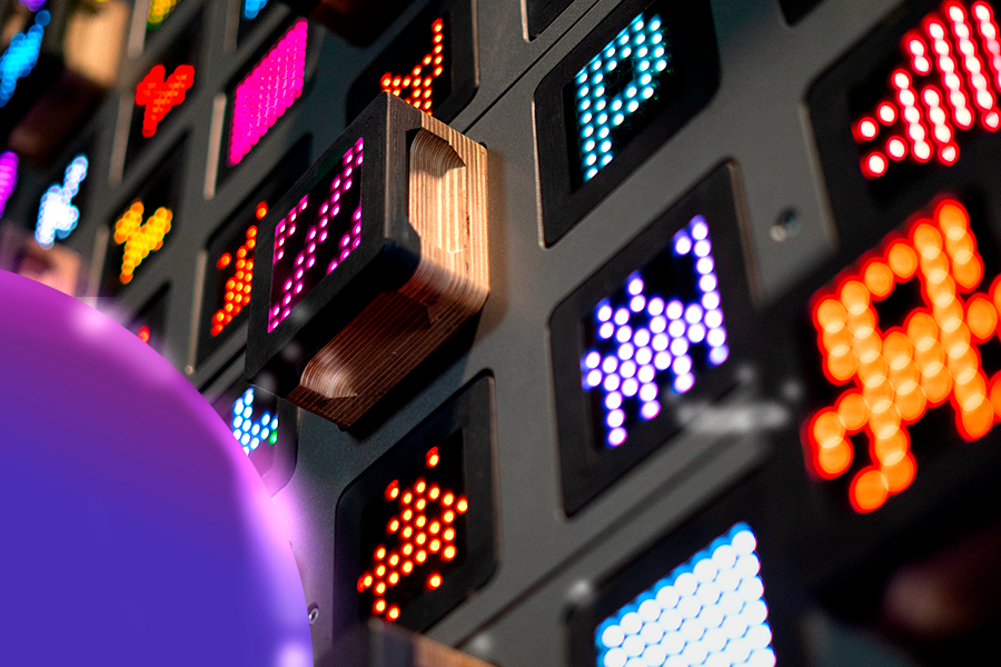 Bliskie ujęcie interaktywnej ścianki wspinaczkowej SkyWall z podświetlanymi chwytami LED w różnych kolorach i kształtach przypominających grafikę retro.