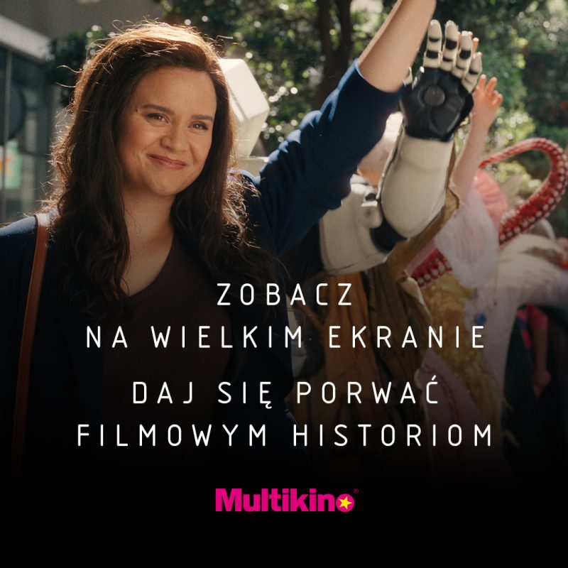 Grafika reklamowa sieci Multikino przedstawia uśmiechniętą kobietę z uniesioną ręką, za którą widoczne są barwne postacie, w tym ramię robota. W dolnej, zaciemnionej części obrazu umieszczono biały napis „ZOBACZ NA WIELKIM EKRANIE DAJ SIĘ PORWAĆ FILMOWYM HISTORIOM” oraz różowe logo marki.