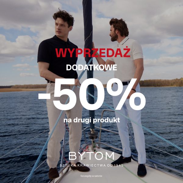 Zdjęcie przedstawia dwóch mężczyzn ubranych w eleganckie koszulki polo i jasne spodnie, pozujących na pokładzie jachtu żaglowego na tle wody i nieba. Na środku obrazu znajduje się duży napis promocyjny marki Bytom informujący o wyprzedaży i rabacie -50% na drugi produkt.