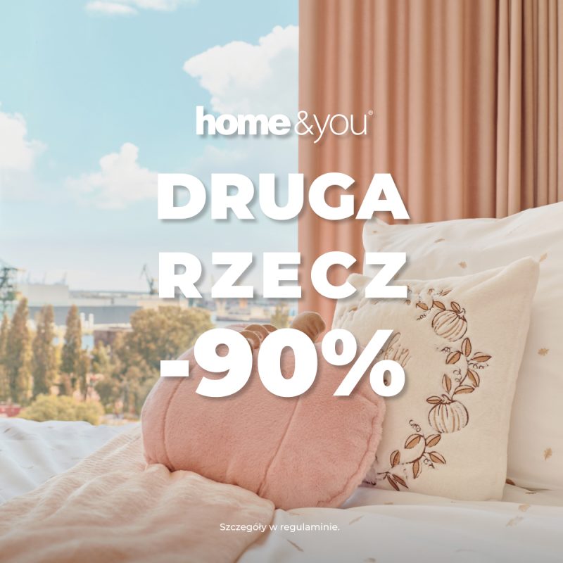 Kwadratowa grafika promocyjna marki home&you przedstawiająca przytulną sypialnię. Na łóżku z wzorzystą, jasną pościelą leży różowy koc oraz dekoracyjna poduszka w kształcie dyni. W tle widoczne okno z widokiem na miasto i beżowo-różowa zasłona. Na środku umieszczono białe logo home&you i napis DRUGA RZECZ -90%.