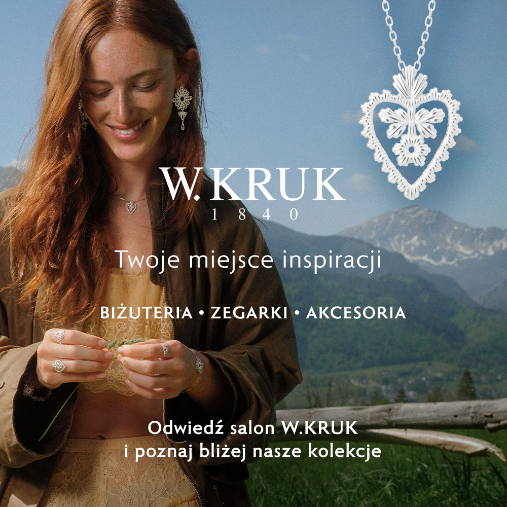 Uśmiechnięta rudowłosa kobieta w górskiej scenerii prezentująca srebrną biżuterię oraz zawieszkę w kształcie serca w kampanii W.KRUK w Galerii Młociny
